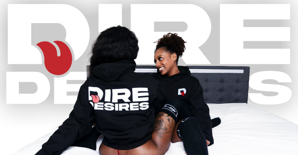 Two people wearing black hoodies with 'Dire Desires' branding in a promotional setting.